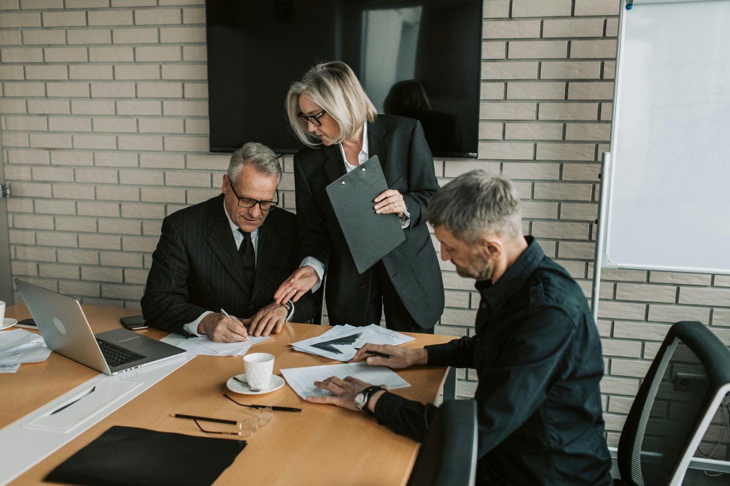 An older business owner signing finance paperwork - working capital and growth funding for established businesses